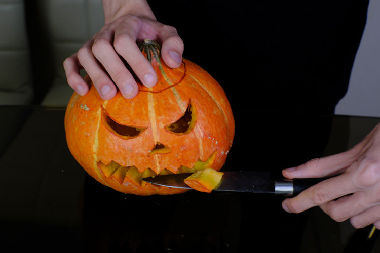 Cropped image of hand holding pumpkin at home