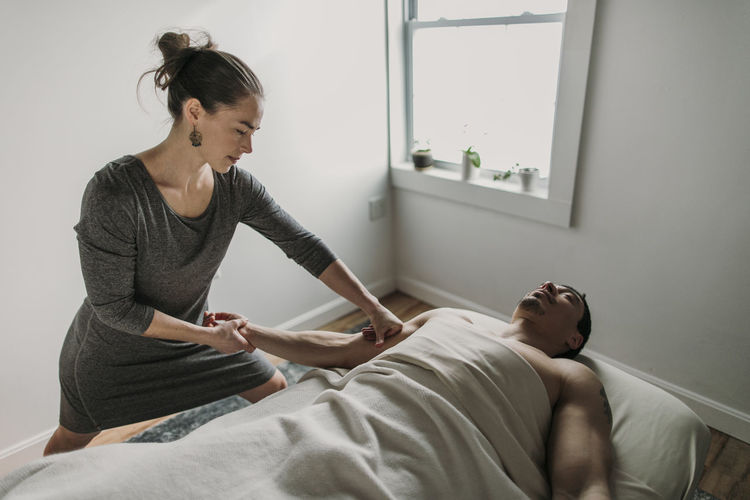A female massage therapist treats a man's bicep
