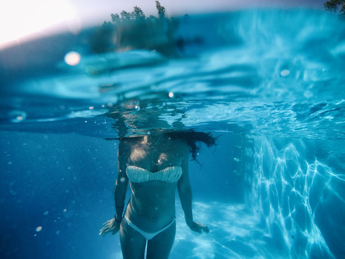 Midsection of pregnant woman swimming in pool
