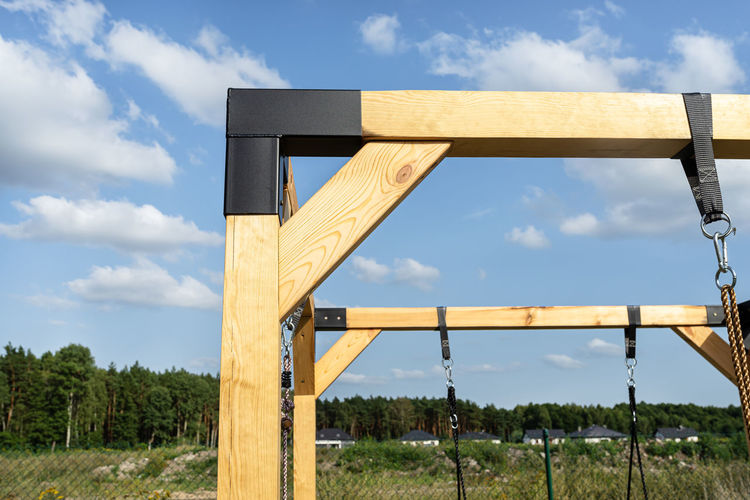 A modern cubic playground made of wooden logs and metal corners, visible steel corners.