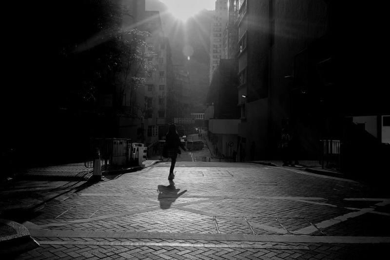 Rear view of woman walking at city street on sunny day