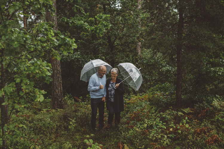 Elderly couple with umbrellas in the woods