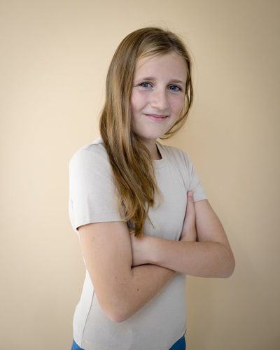 Portrait of young woman standing against wall