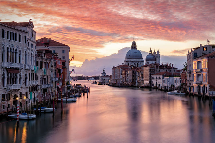 Grand canal amidst buildings in city against sky during sunset