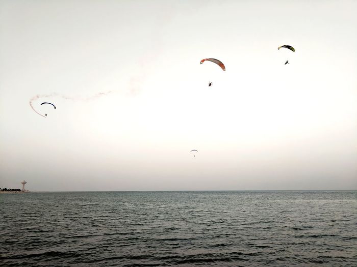 Paragliding over sea against clear sky