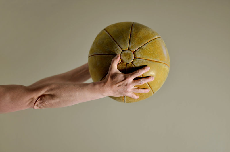 Close-up of hand holding ball against gray background