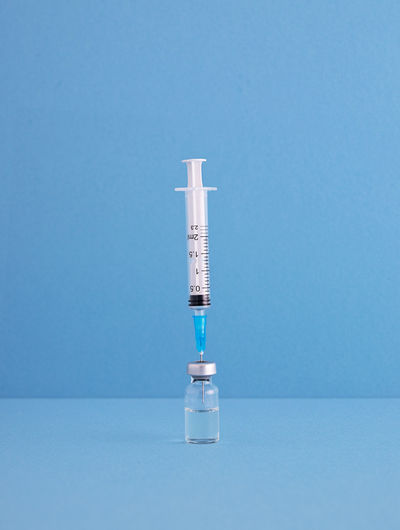 Close-up of syringe with vial on blue background