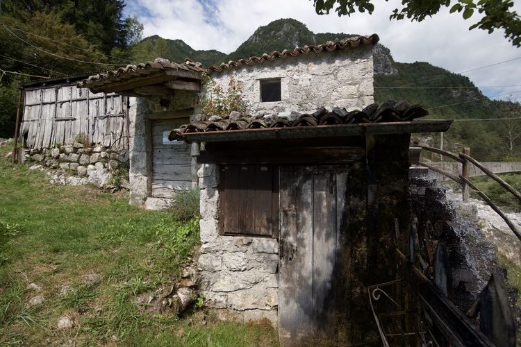 Old building by tree mountain against sky