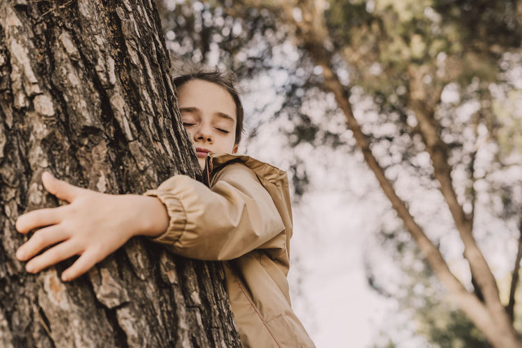 Low angle view of girl on tree trunk