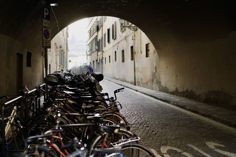 Pandemic lockdown in florence - bicycles parked on street by old building tunnel