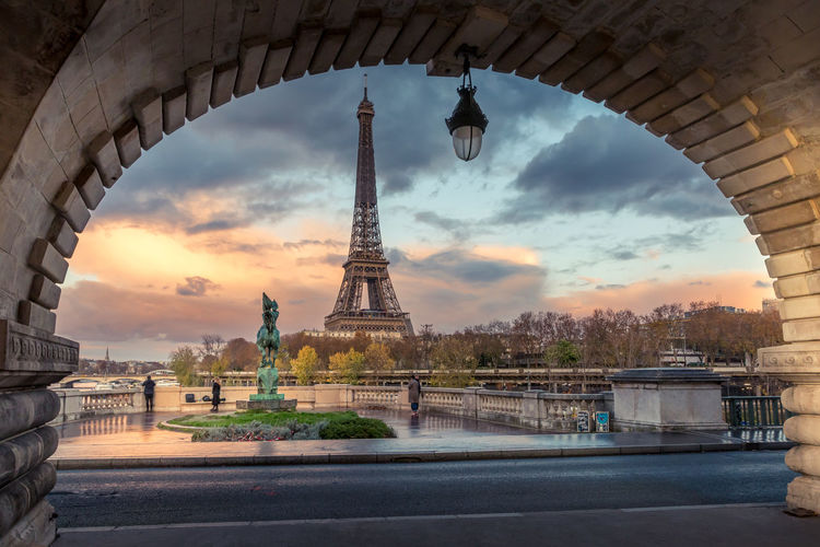 Eiffel tower against cloudy sky during sunset in city