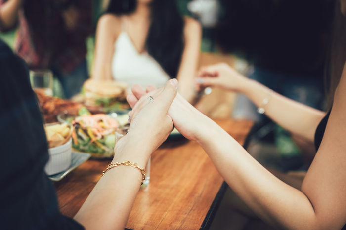 Friends holding hands in restaurant