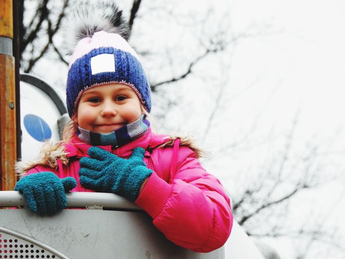 Portrait of girl smiling on play equipment during winter