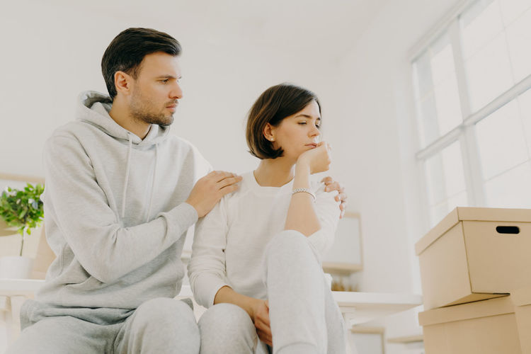 Man consoling woman while sitting at home