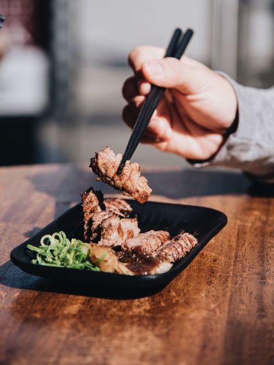 Cropped hand having meat on wooden table