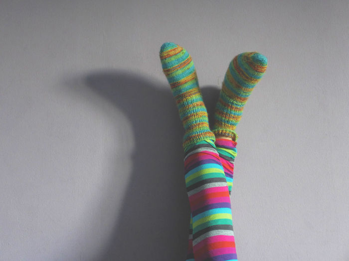 Low section of woman wearing colorful knitted socks against wall