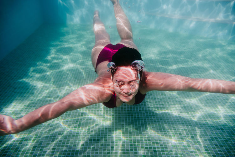 Mid adult woman swimming underwater in pool