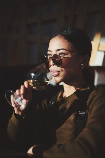 Close-up of woman looking away while sitting at restaurant and drinking wine