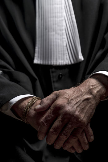 Midsection of lawyer standing against black background