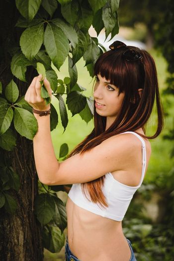 Side view of woman standing by tree