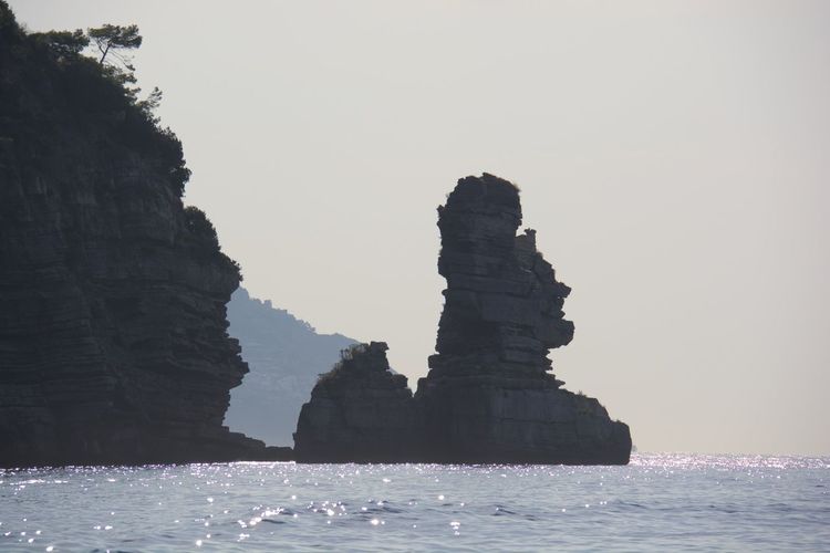 Rock formations in sea against clear sky