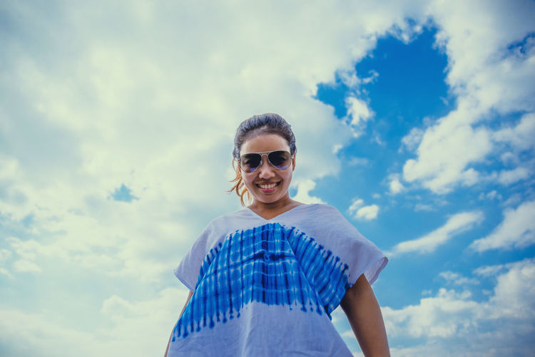 Low angle view of portrait smiling woman standing against sky