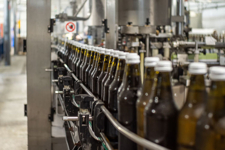 Brown glass bottles of drinking water move on the conveyor belt in the production hall