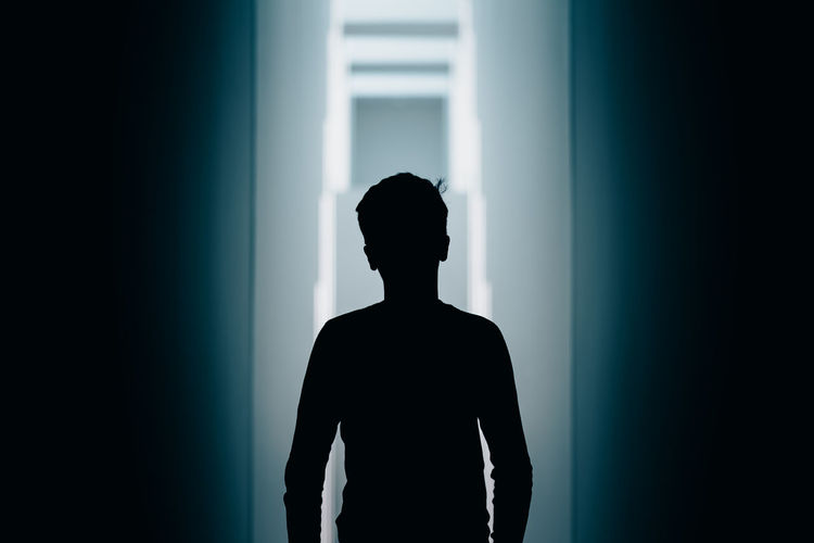 Silhouette man standing against wall