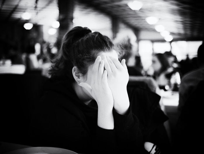 Close-up of girl covering face while sitting at restaurant