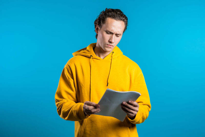 Man holding yellow while standing against blue background