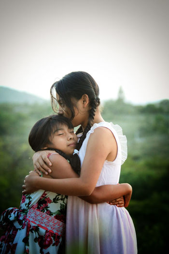 Two girls showing affection by burning with a view towards the forest 