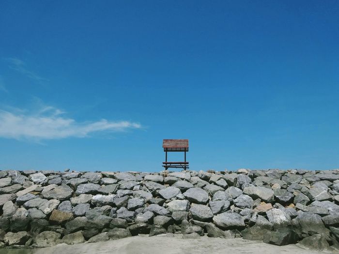 Lifeguard hut on rocks against blue sky