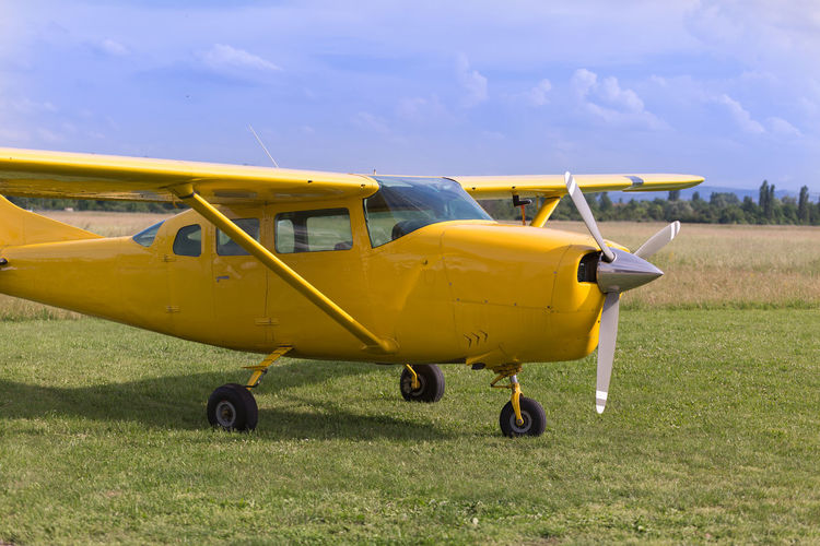 Yellow airplane on field against sky