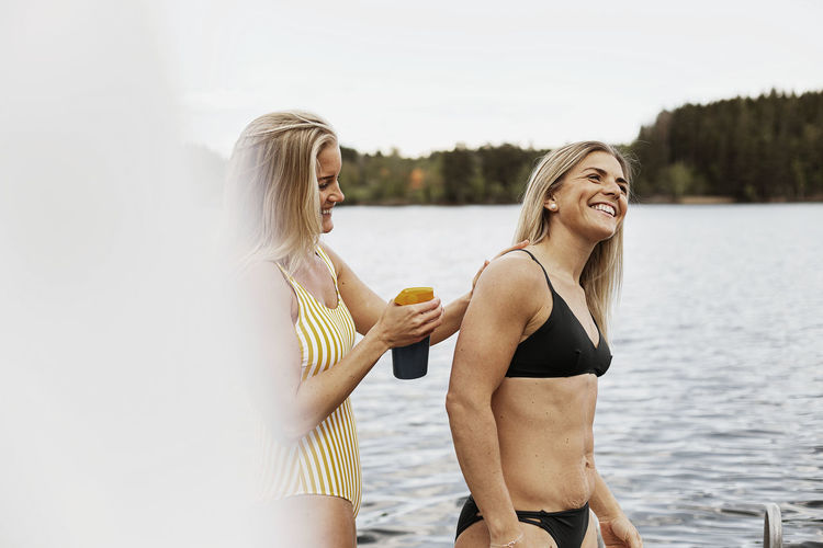 Smiling women applying sunscreen at lake