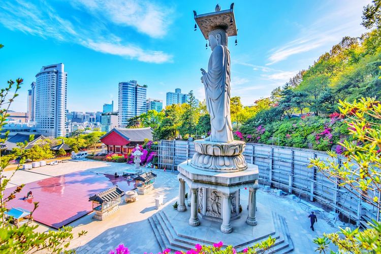 Statue amidst buildings in city against sky