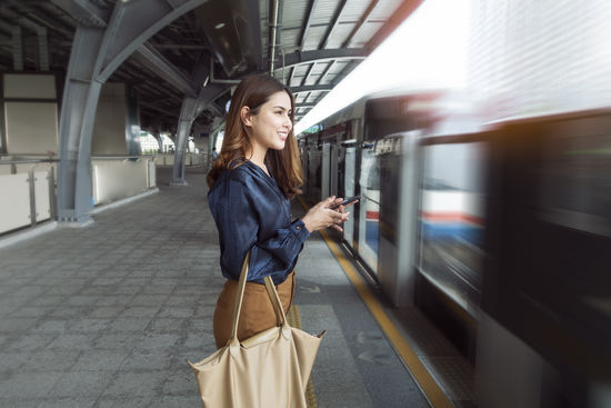 Young woman using mobile phone while standing on train