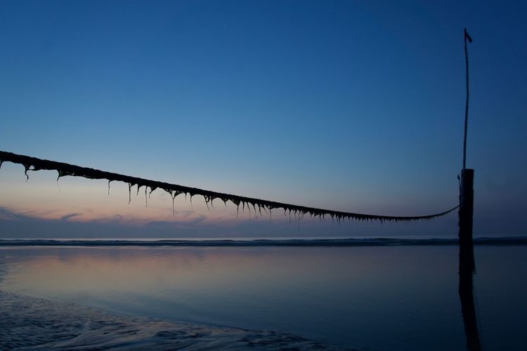 Silhouette bridge over water against clear sky during sunset