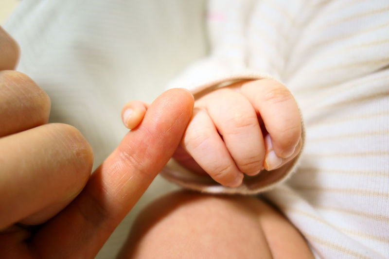 Close-up of baby holding mother hand