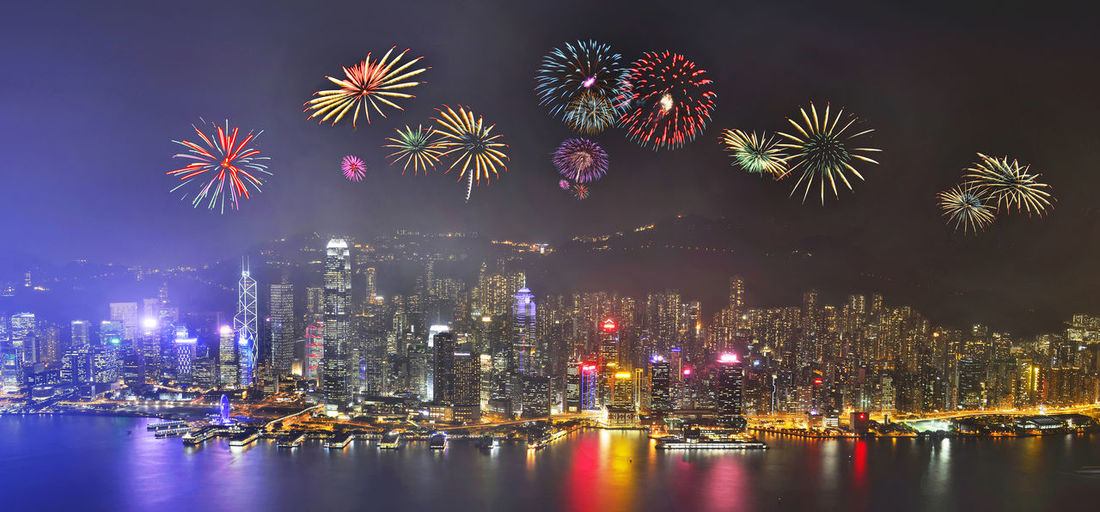Firework display over river against sky at night
