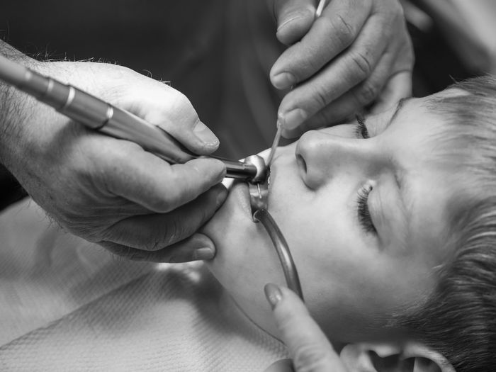 Close-up of dentist drilling the teeth of boy at clinic