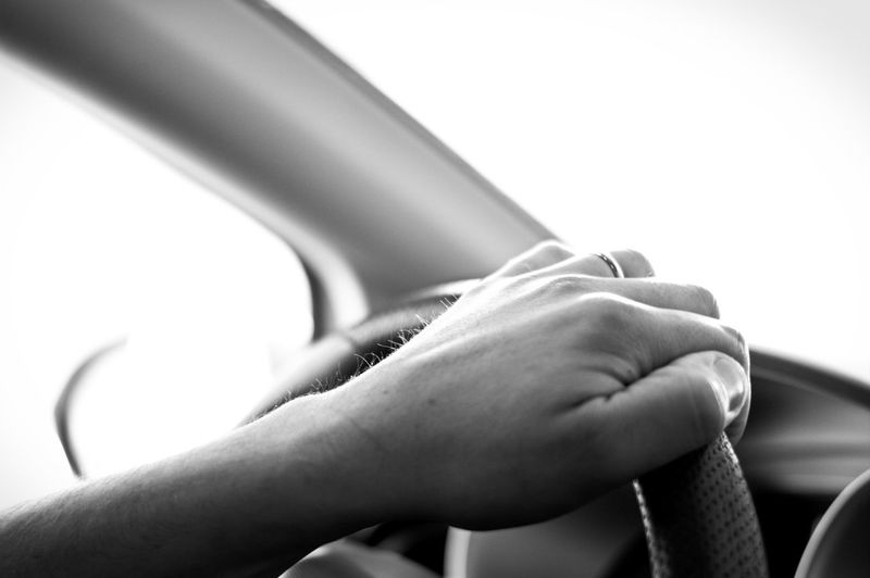 Cropped hand of woman on steering wheel