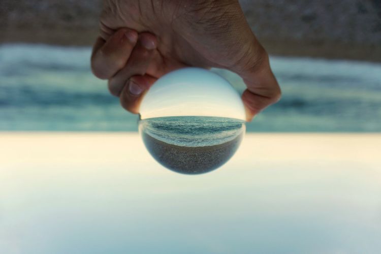 Close-up of hand holding ball on beach