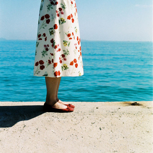 Low section of woman standing at beach