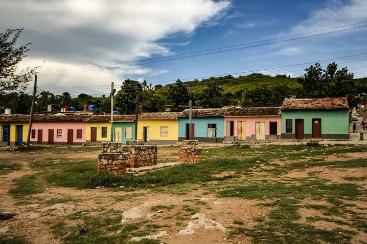 Old house on field by building against sky