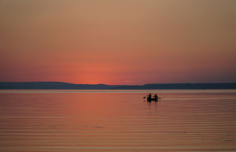 Silhouette of people on boat in lake