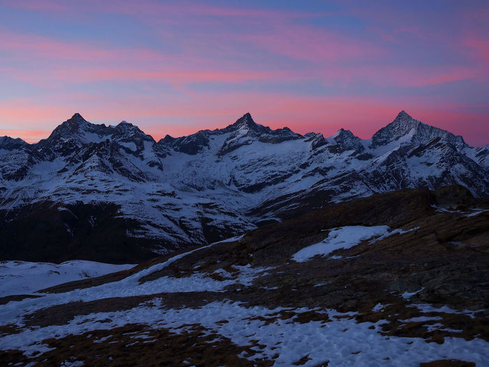 Scenic view of snow mountains against sky at sunset