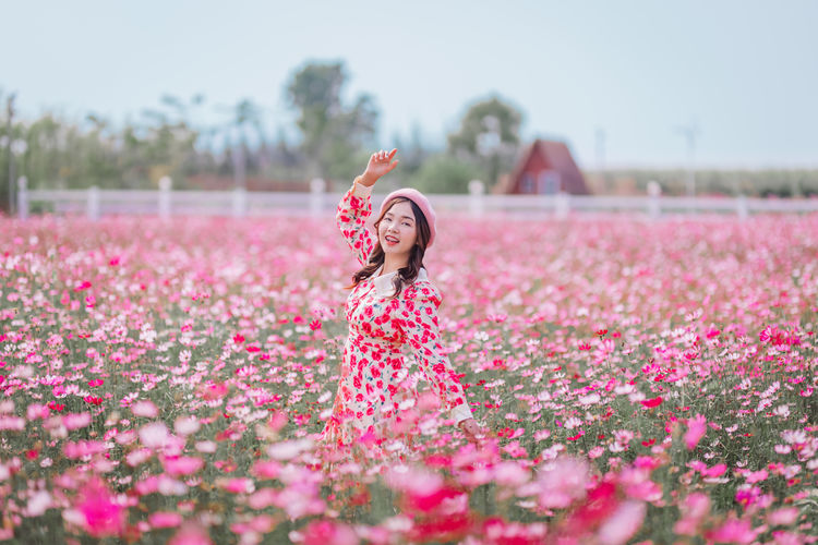 Woman standing by pink flowers on field