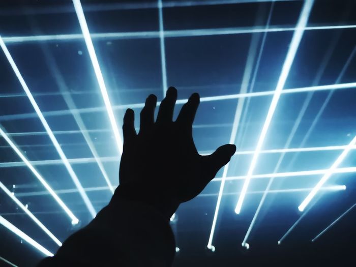Silhouette of person touching illuminated light