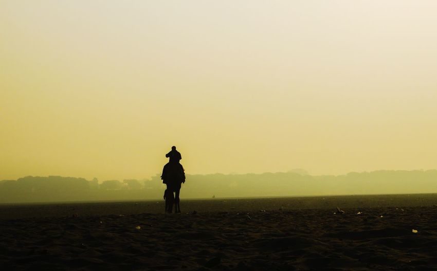 Silhouette man standing on field against clear sky during sunset