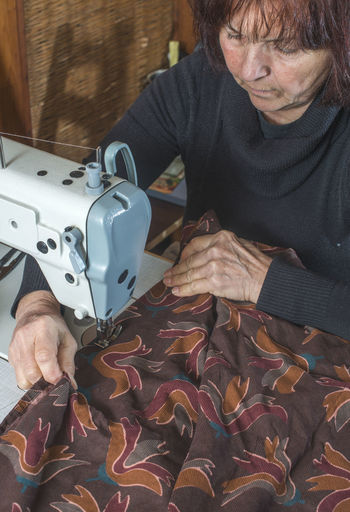 High angle view of tailor sewing textile